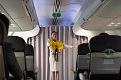 Flight attendant explaining airline safety regulations and showing the emergency exits to passengers on airplane cabin