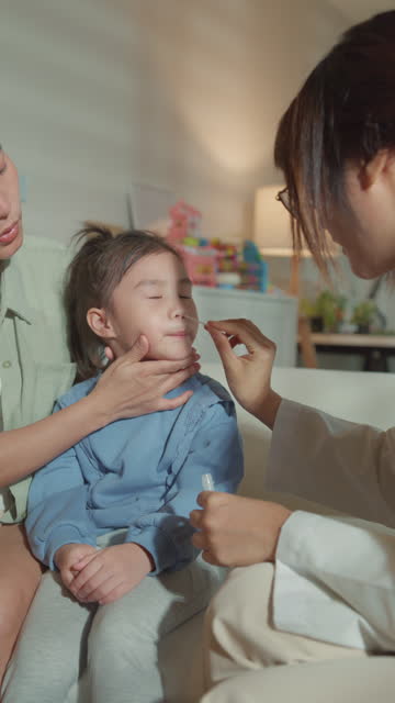 Asian girl, who gets sick and has a high fever, does Nasal swabs from a doctor at home. Illness Girl stays with her mom with a medical condition and family wellness. Vertical Screen.