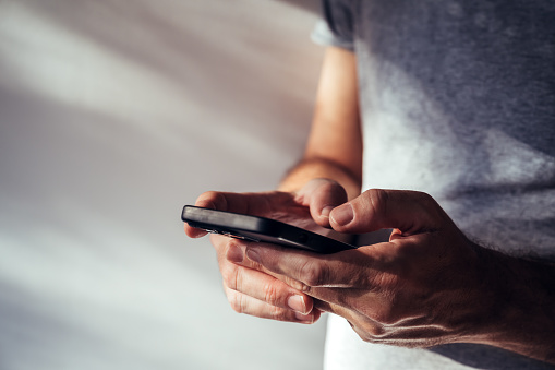 Man using modern smartphone portable information device to type text message, selective focus