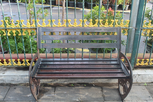 Iron bench in the garden with iron fence in the background