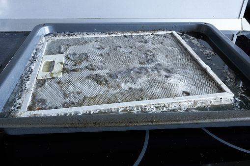 Cleaning the kitchen hood filter, close-up photo. Cleaning the filter from dust. Anti-grease agent.