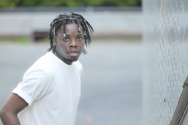 a young man with his hairstyle and the atmosphere of living in the community. - black ladder white staircase photos et images de collection