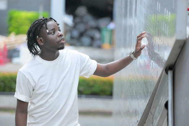 a young man with his hairstyle and the atmosphere of living in the community. - black ladder white staircase photos et images de collection