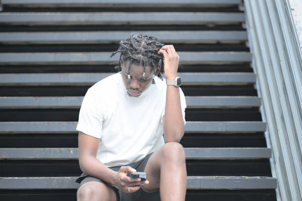 a young man with his hairstyle and the atmosphere of living in the community. - black ladder white staircase photos et images de collection