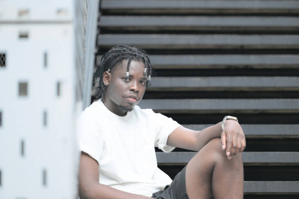 a young man with his hairstyle and the atmosphere of living in the community. - black ladder white staircase photos et images de collection