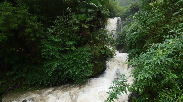 Waterfall in rainy season. Fast flowing waterfall river between canyon. Soil and mud is moving towards down after strong rain. Giant roiling brown muddy water. 4k slow motion footage b roll shot.