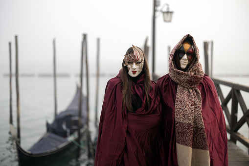Venice, VE, Italy - February 13, 2024: two people with white masks on the seashore
