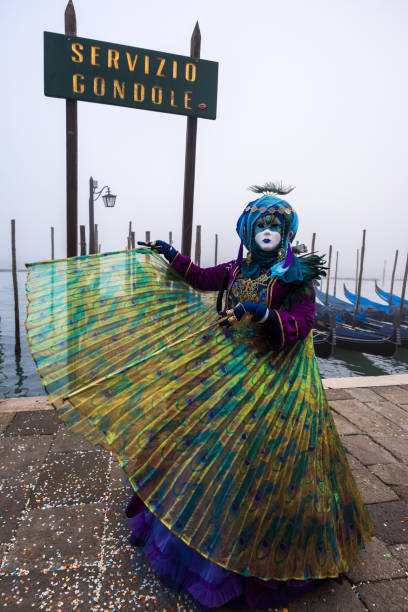 costume da maschera di carnevale veneziano pavone femminile che balla e posa sul lungomare di san marco - mardi gras carnival peacock mask foto e immagini stock