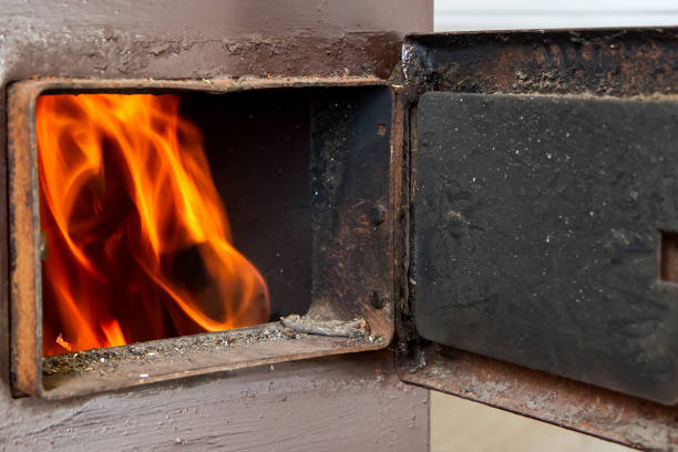 A fire burns in a wood-burning boiler. Open furnace door.