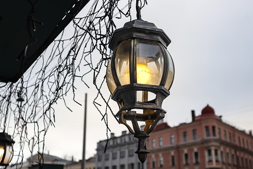 Lamps shine in the evening sky on O'Connell Street in central Dublin, Ireland. The O'Connell Monument and the Spire of Dublin (also called the Monument of Light) are in the background.