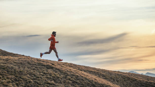 istock Sporty man runs in training on downhill meadow 1989429758