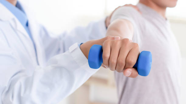 istock Doctor or Physiotherapist helping man exercise with dumbbell and physical therapy help for muscle or arthritis exercise in consulting exam. Doing the Rehabilitation therapy pain in clinic. 1989434032