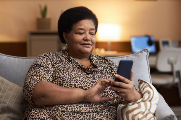istock Black Senior Woman Using Phone in Cozy Home 1989444369