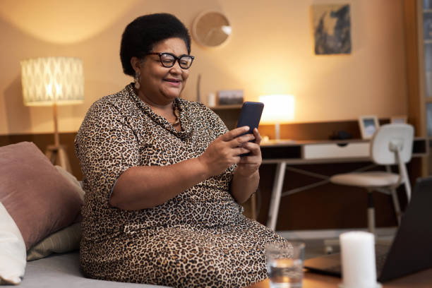 istock Senior Black Woman Holding Phone Using Online Messaging 1989444385