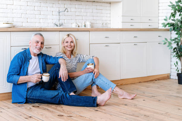 istock Smiling middle aged man and woman sitting on kitchen floor fun spending time 1989464803