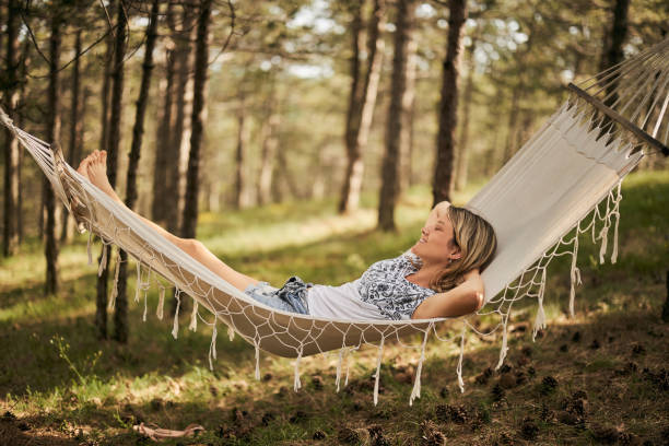 Young happy woman relaxing with her eyes closed in hammock in nature.
