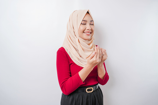 Happy beautiful Asian Muslim girl wearing a headscarf praying to God.