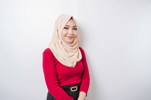 Portrait of a confident smiling Asian Muslim woman standing and looking at the camera isolated over white background