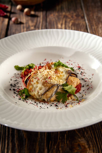 istock Baked eggplant roll with cheese and tomatoes, elegantly plated on a white dish 1989509644