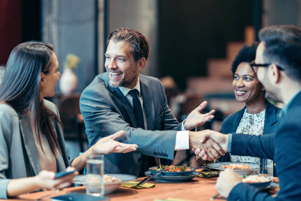 istock Businessmen shaking hands across the table in a restaurant 1989515948