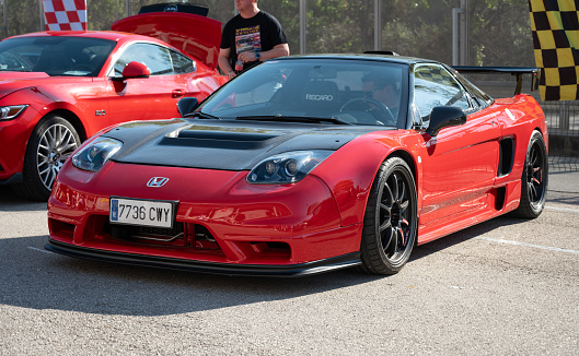 Montmelo, Spain – December 15, 2023: Front view of a stunning mid-engine V6 Honda NSX. It is red with black carbon fiber mirrors and hood and Recaro seats at the expo.