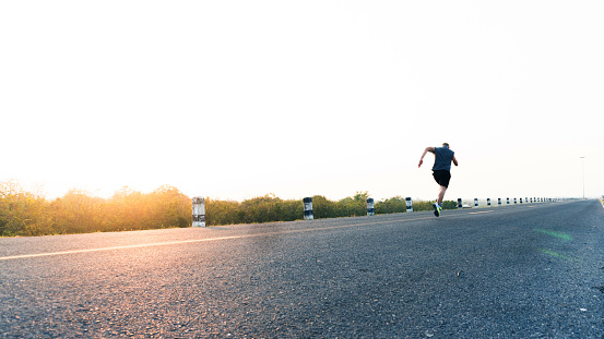 The man with runner on the street be running for exercise. Sport Backgrounds, Male runner ready for sports exercise, Athlete running on athletic track. Athlete runner feet running on road