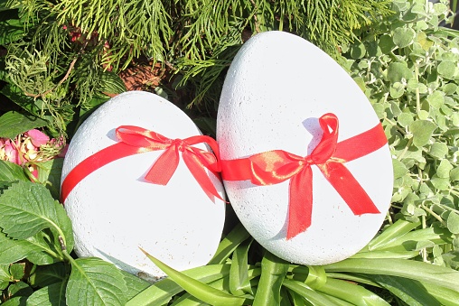 Decorated easter white eggs with ribbon at nest. Easter decoration. Egg hunt concept. Traditional Easter holiday composition