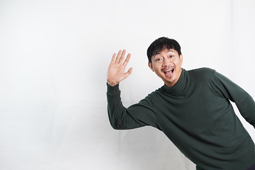 Young man standing over white background waiving saying hello happy and smiling, friendly welcome gesture. Hi five concept