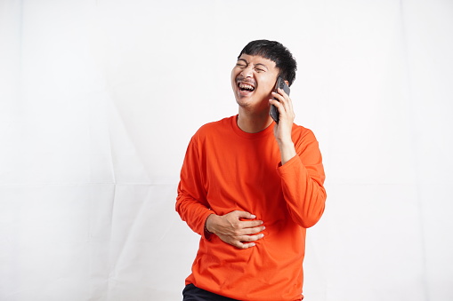 male laughing holding his hands on stomach can`t stopping laughing after hearing funny anecdote on call