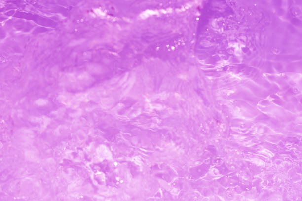 Water surface. Purple water waves on the surface ripples blurred. Defocus blurred transparent blue colored clear calm water surface texture with splash and bubbles. Water waves with shining pattern.