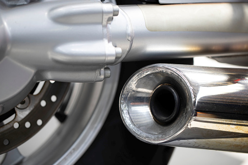 close up rear view of a powerful classic black vintage motorcycle showing suspension and shiny chrome exhaust pipe