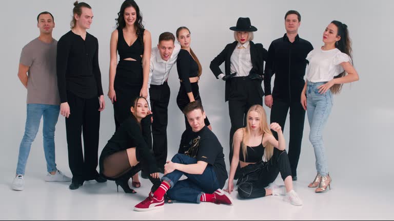 group of young happy people standing in dance studio, looking at camera