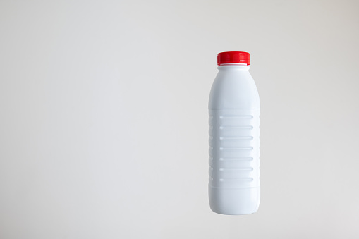 White opaque plastic bottle with a red cap isolated on white background, no label.