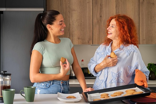 Mother and daughter show love with fresh-baked homemade heart shaped butter cookies. Family time.