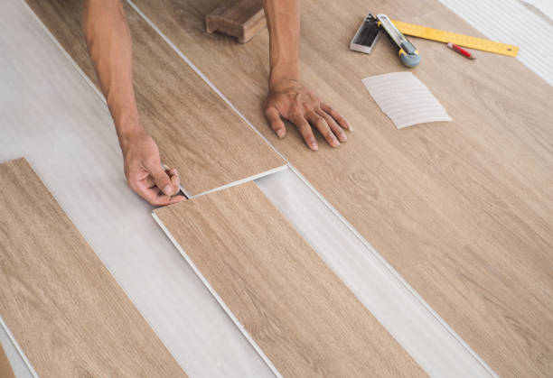 a technician is cutting luxury vinyl floor tiles with a cutter to lay the floor before placing it on the leveling foam. - golv bildbanksfoton och bilder