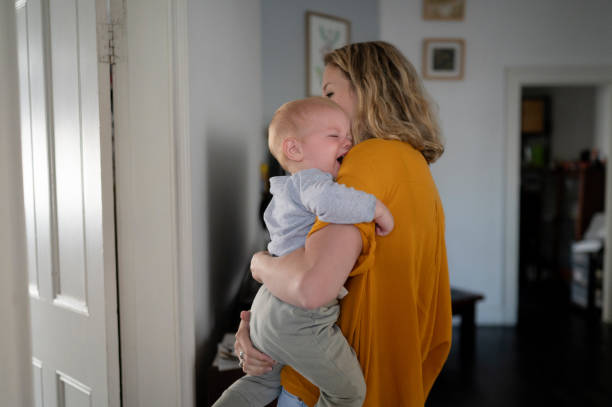 Comfort, crying or tantrum with mother and baby in home together for love, support or childcare. Family, sad and stress with woman parent hugging son in apartment for tears, emotion or upset stock photo