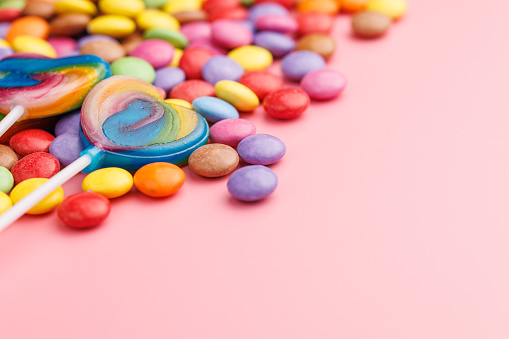 Colorful sweet jelly candies and lollipops. Sweet candies on the pink background.