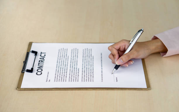 istock Closeup woman hand signing her name on a contract document on a board. 1989653186