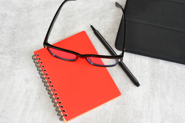 red notepad with black glasses and black pen