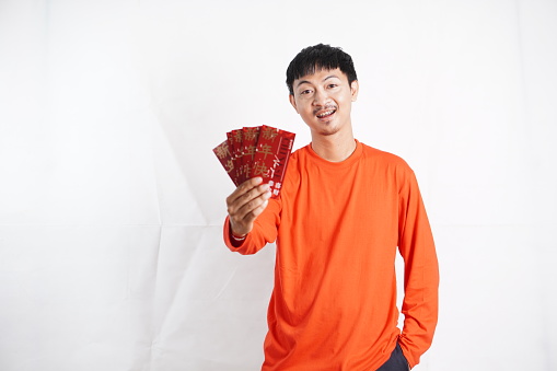 Happy Chinese new year. Asian man holding angpao or red packet monetary gift isolated on white background. Show good luck, greetings, and congratulations