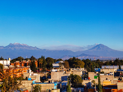 Beautiful postcard of the landscape of the Popocatépetl and Iztaccíhuatl volcanoes, on a day with clean and clear blue skies, seen from Mexico City.