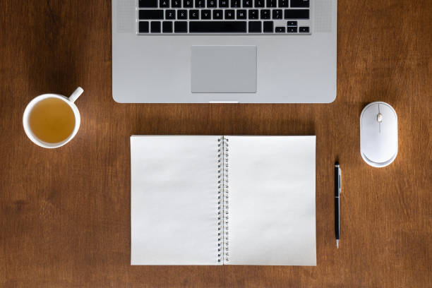istock Laptop, cup of tea and notepad on a wooden table, top view. 1989671473