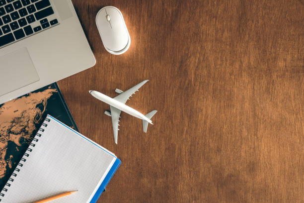 istock Airplane miniature, notepad, World map and laptop on a wooden table. 1989674426