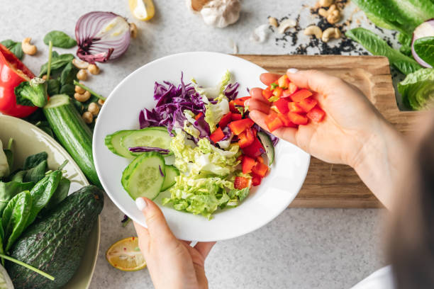 istock A plate with chopped fresh vegetables in female hands in the kitchen, top view. 1989680235