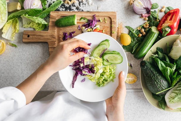 istock A plate with chopped fresh vegetables in female hands in the kitchen, top view. 1989680236