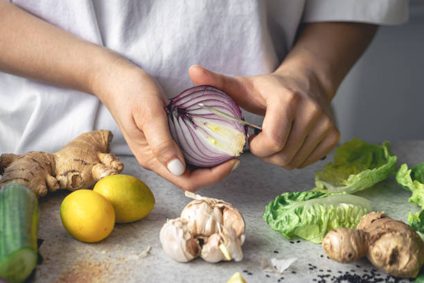 istock A woman cuts onions for salad on the kitchen table, close-up. 1989683351