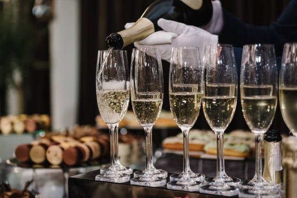白スパークリングワインを注ぐウェイター。ケータリングサービスのコンセプト。バーテンダーはフルートグラスにシャンパンを注ぐ。グラスに注がれているシャンパン。クローズアップビ� - party business toast champagne ストックフォトと画像
