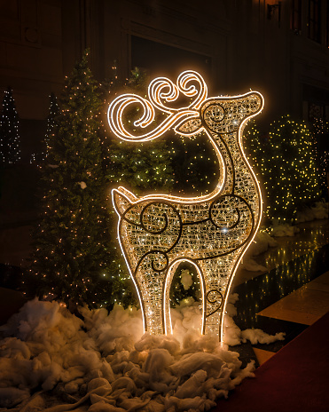 A vertical of festive reindeer lights in a park at night