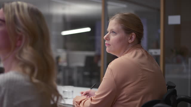 Woman listening to a presentation in the meeting room alongside her coworkers