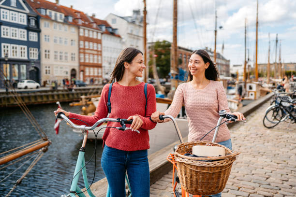 two female friends with bicycles in nyhavn canal in copenhagen in denmark - öresund ストックフォトと画像